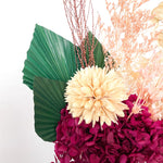 A mix of preserved flowers and silk flowers of hydrangea, magnolia flower, cherry blossom, honesty, nigella, cloudy leaf, misty and palm in a in white vase.